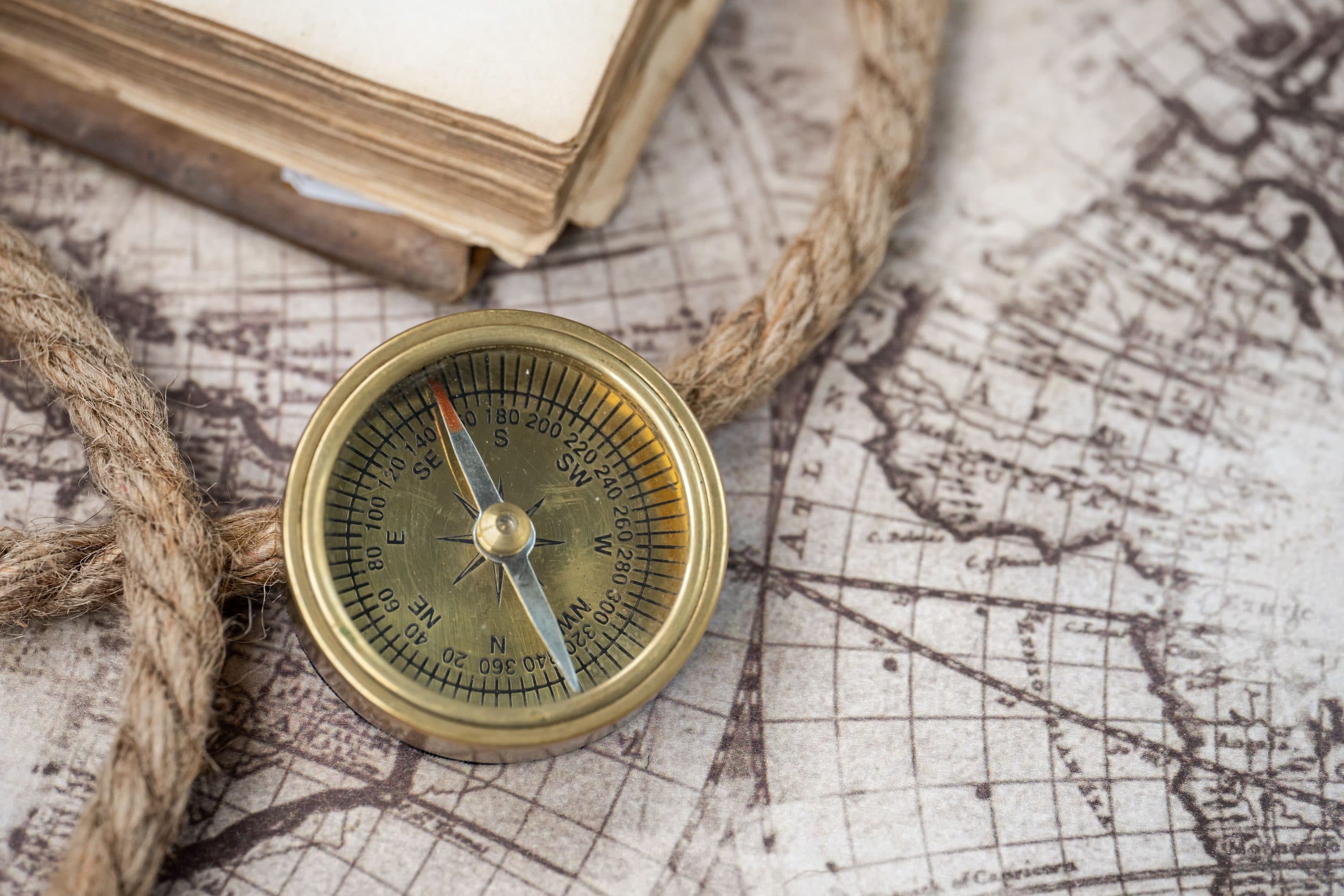 A brass compass resting on an old nautical map