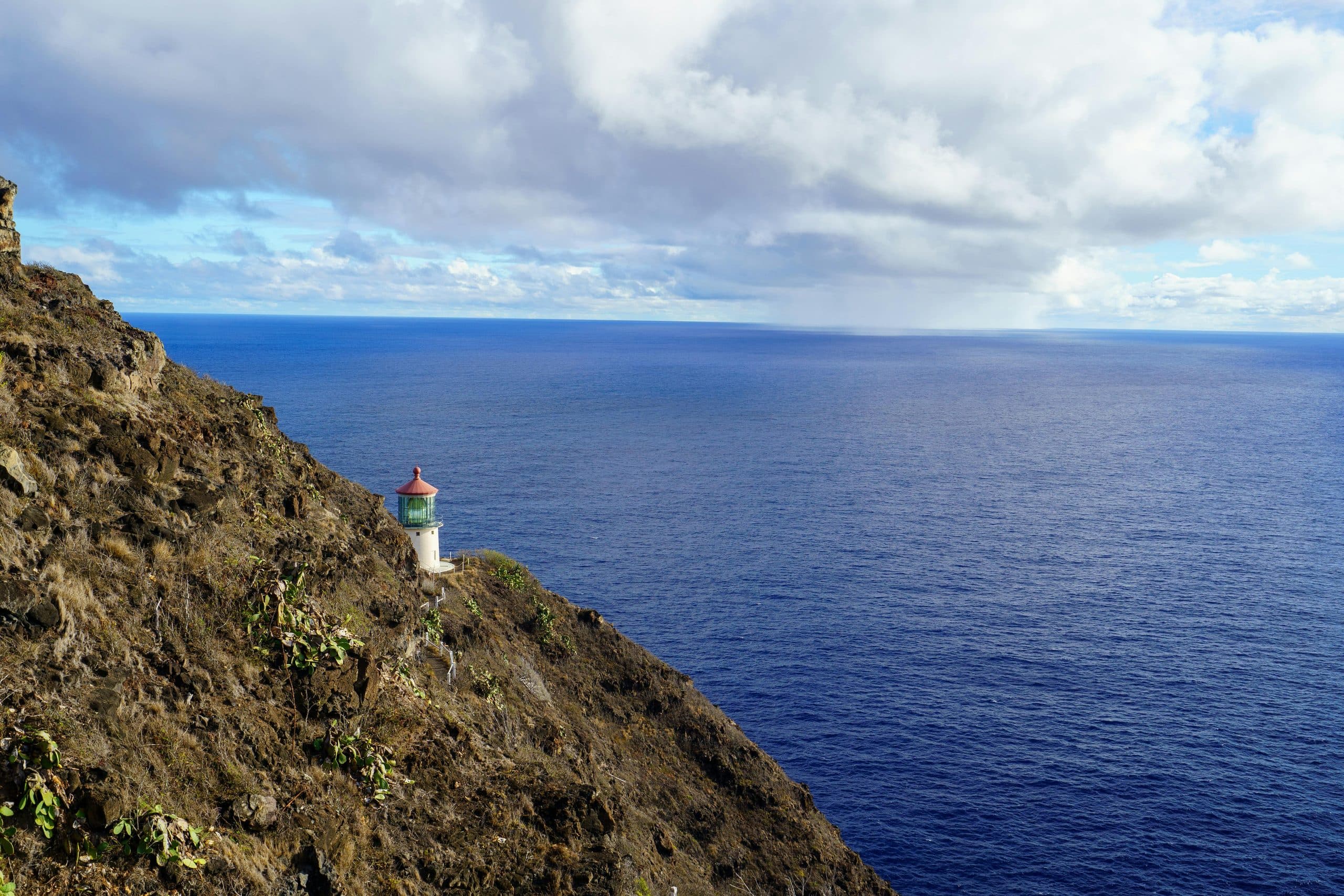 A lighthouse on a cliff above deep blue ocean